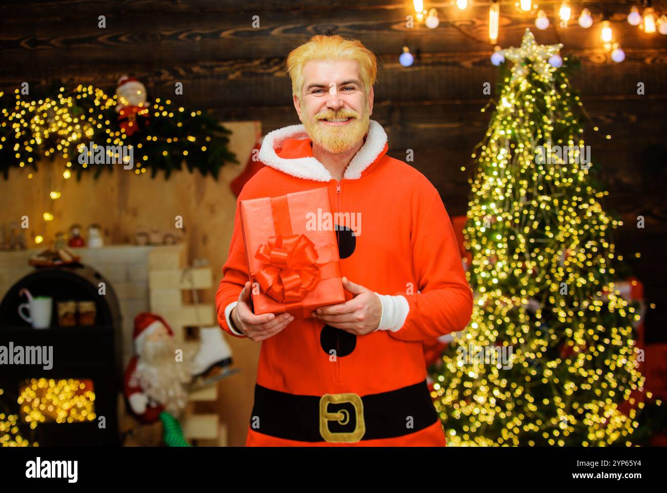 Frohe Weihnachten und frohes neues Jahr. Lächelnder Weihnachtsmann mit Weihnachtsgeschenk. Bärtiger Mann in Weihnachtskleidung mit Weihnachtsgeschenk. Weihnachtsmann mit Christma Stockfoto