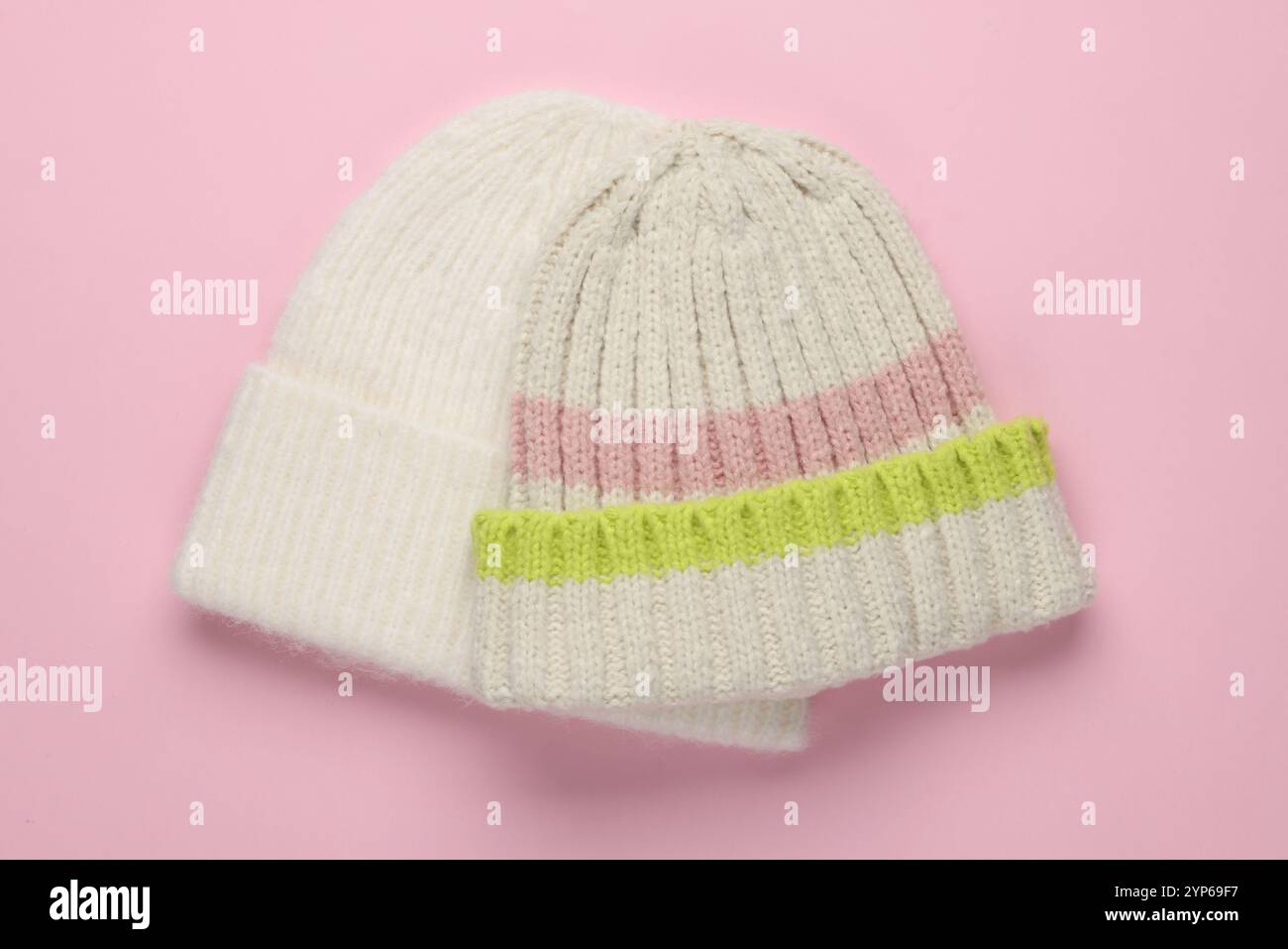 Warme Wollmützen auf hellrosa Hintergrund, Draufsicht Stockfoto