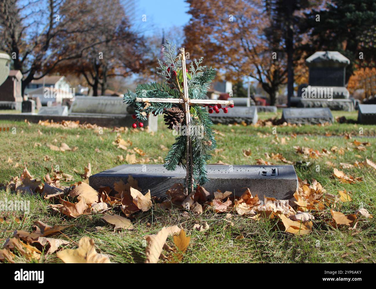 Holzkreuz mit immergrünen Zweigen und stechpalmenbeeren auf einem Friedhof in einem Vorort von Chicago Stockfoto