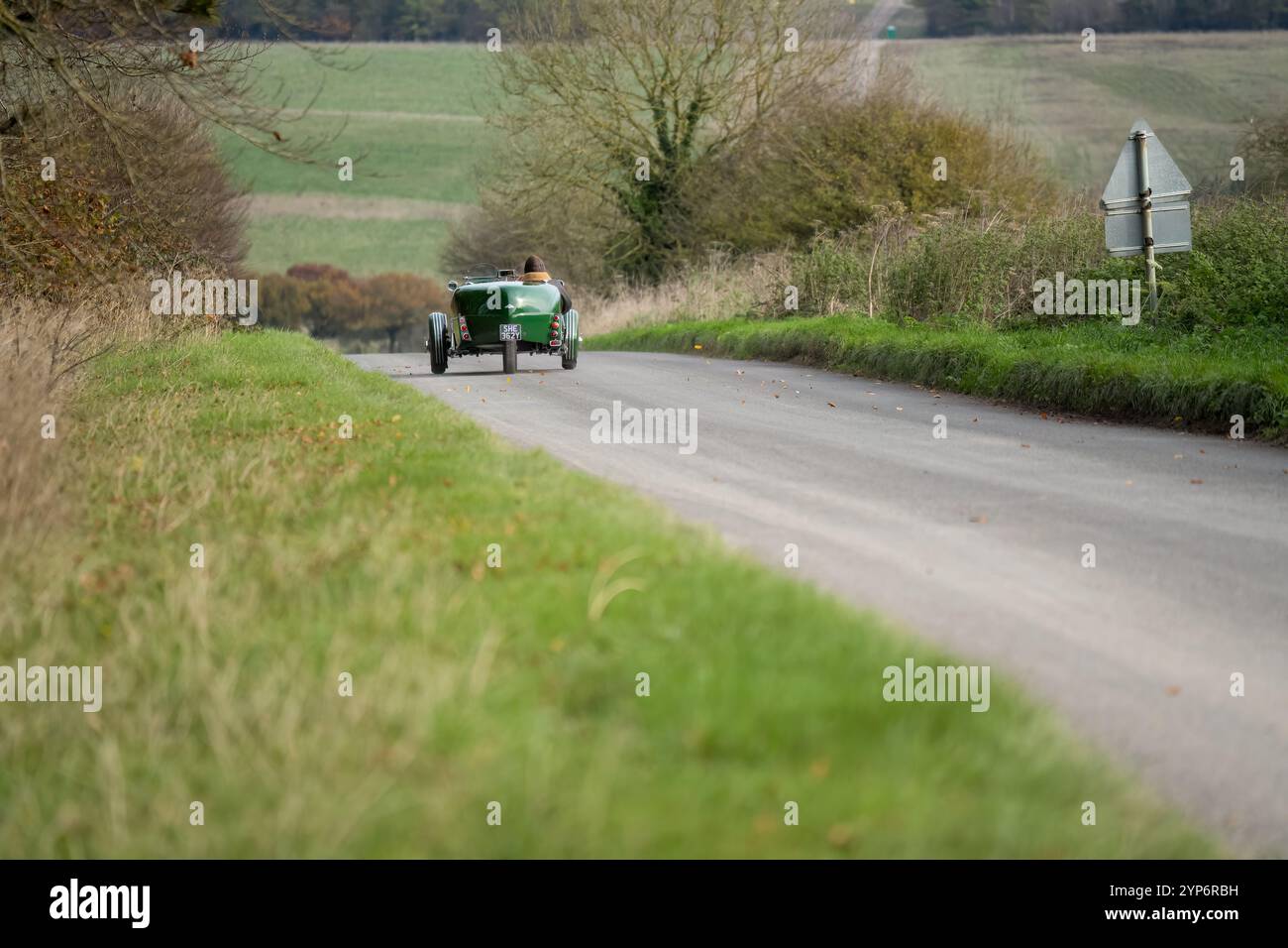 Ein grünes, dreirädriges, zweisitziges Roadster-Kit-Auto mit offenem Oberdeck von Lomax 223, das auf einer Landstraße fährt Stockfoto