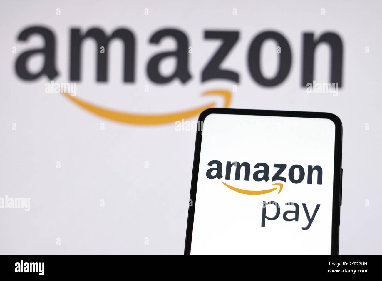 In dieser Abbildung wird das Amazon Pay Logo auf einem Smartphone und im Hintergrund das Amazon Logo angezeigt Stockfoto