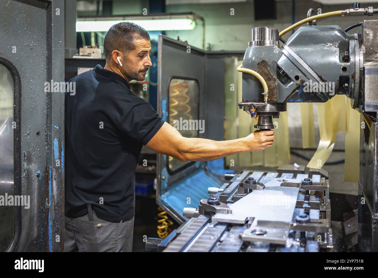 Männlicher Bediener, der Musik hört und mit der Fräsmaschine in der cnc-Fabrik arbeitet Stockfoto Männlicher Bediener, der Musik hört und mit der Fräsmaschine in der cnc-Fabrik arbeitet Stockfoto