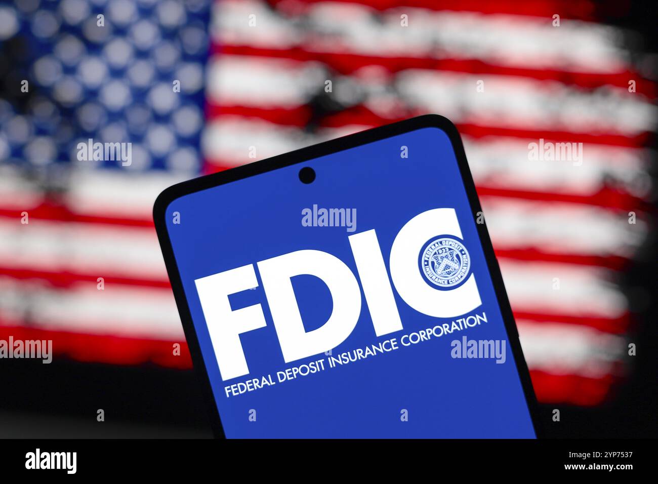In dieser Abbildung wird das Logo der Federal Deposit Insurance Corporation (FDIC) auf einem Smartphone-Bildschirm und im Hintergrund die Flagge o angezeigt Stockfoto
