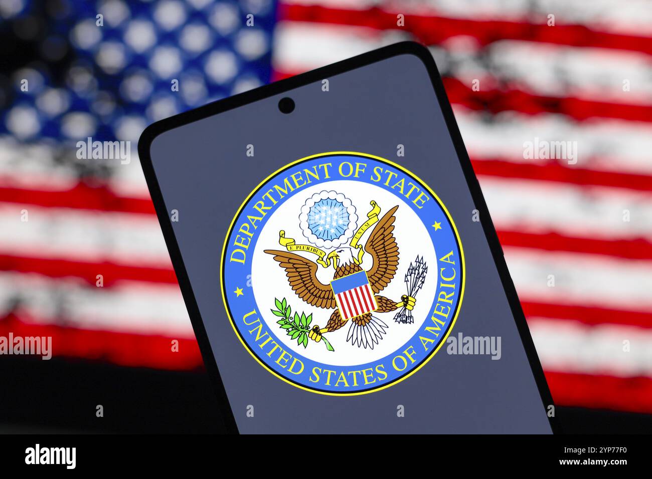 In dieser Abbildung wird das Logo des US-Außenministeriums (DOS) auf einem Smartphone-Bildschirm und im Hintergrund die Flagge des angezeigt Stockfoto