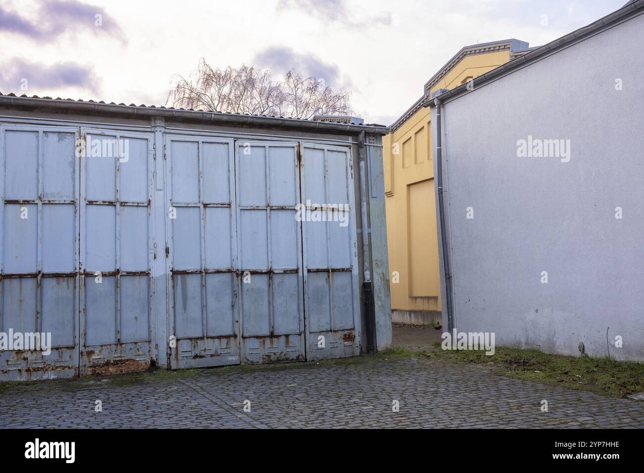 Ein Industriegebiet mit blauen Garagentüren und Betonwänden unter bewölktem Himmel Stockfoto