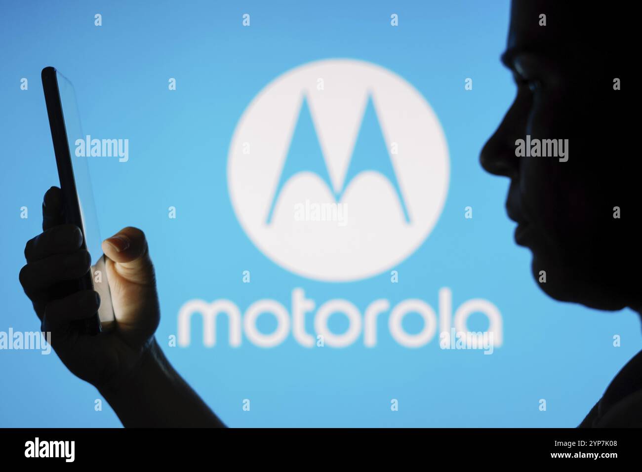 In dieser Fotoabbildung ist das Motorola Mobility Logo im Hintergrund einer Silhouette einer Frau zu sehen, die ein Mobiltelefon hält Stockfoto