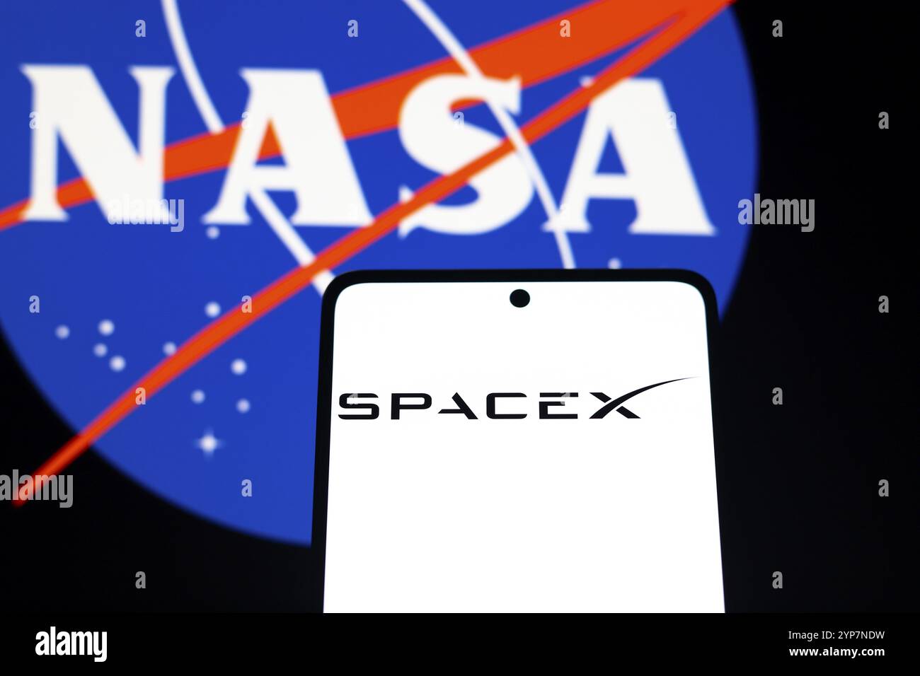 In dieser Fotoabbildung wird das SpaceX-Logo auf einem Smartphone-Bildschirm und im Hintergrund das NASA-Logo angezeigt Stockfoto