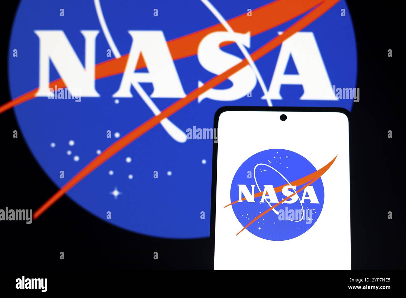 In dieser Fotoabbildung wird das Logo der NASA (National Aeronautics and Space Administration) auf einem Smartphone-Bildschirm und im Hintergrund angezeigt Stockfoto