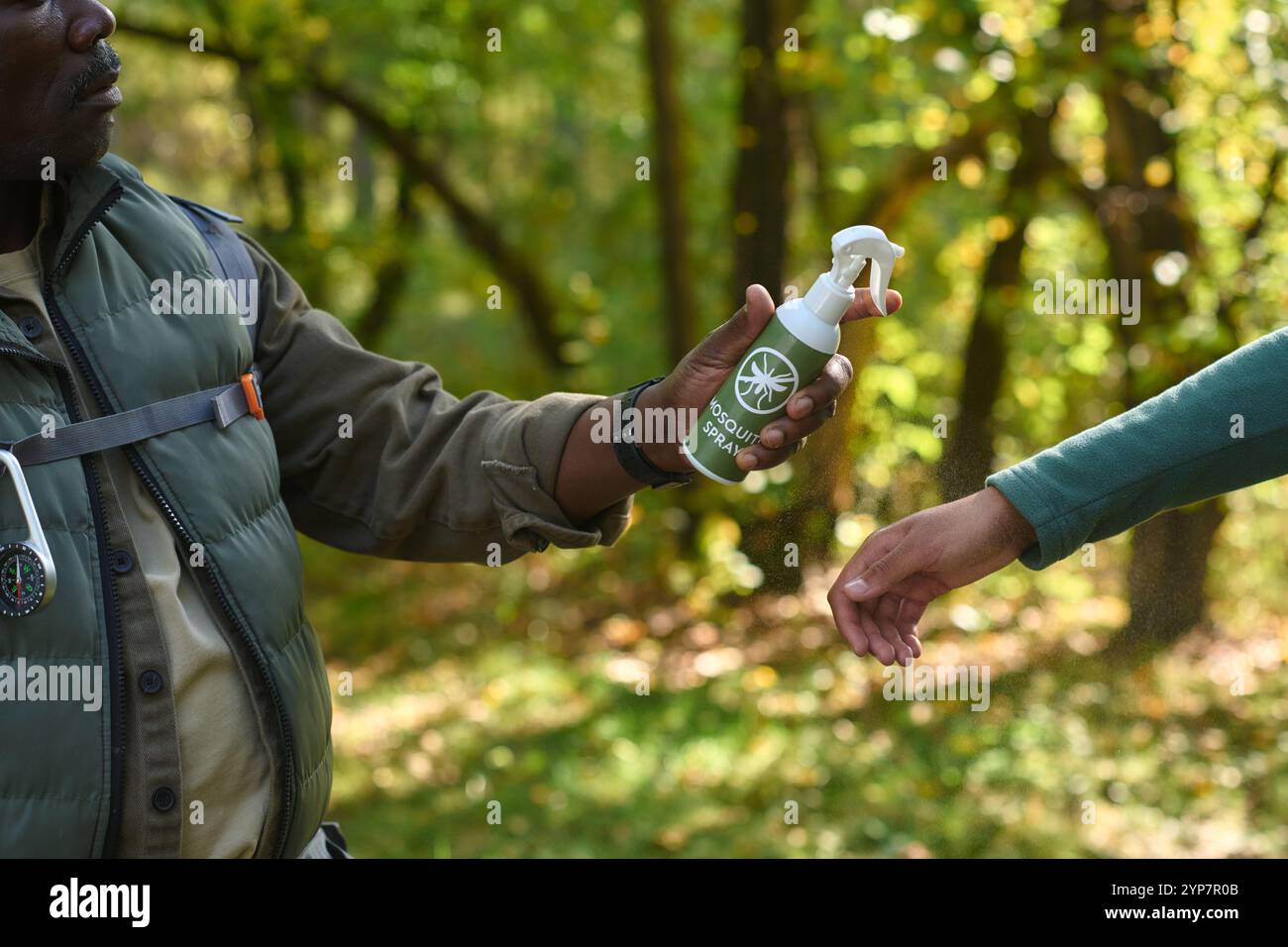 Mittlere Nahaufnahme eines nicht erkennbaren Mannes, der Mückenspray hält und bereit ist, es auf die Kinderhand zu sprühen Stockfoto