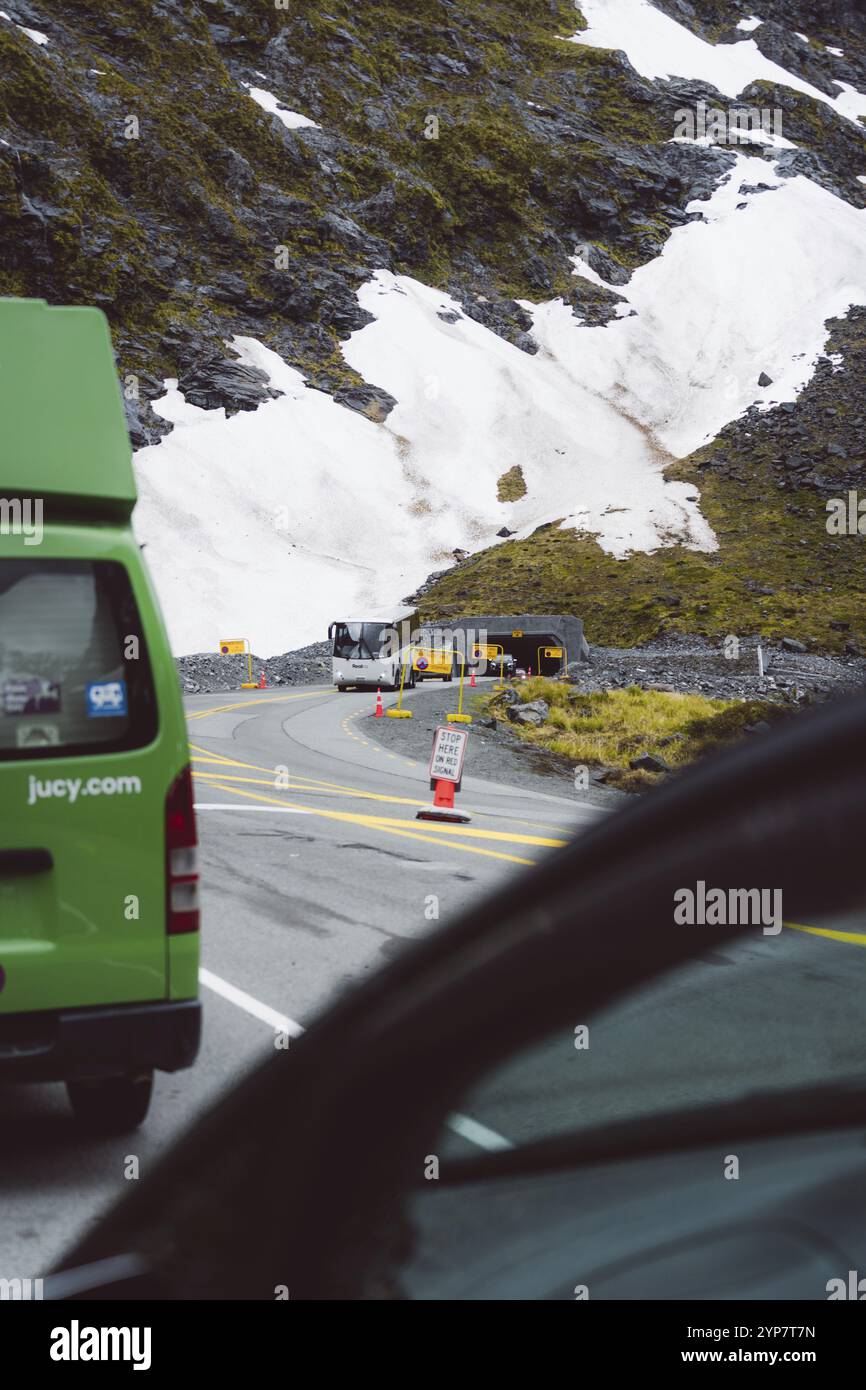 Grüner Van auf gewundenen Bergstraßen mit Resten von Schnee und Warnschildern, Milford Sound, Neuseeland, Ozeanien Stockfoto