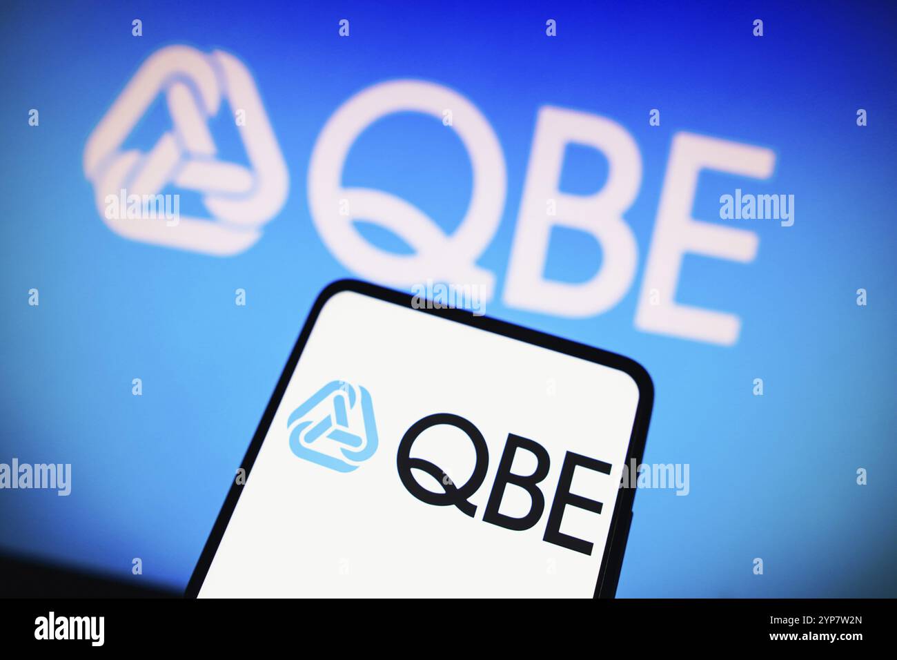 In dieser Abbildung wird das Logo der QBE Insurance Group Limited auf einem Smartphone und im Hintergrund angezeigt Stockfoto