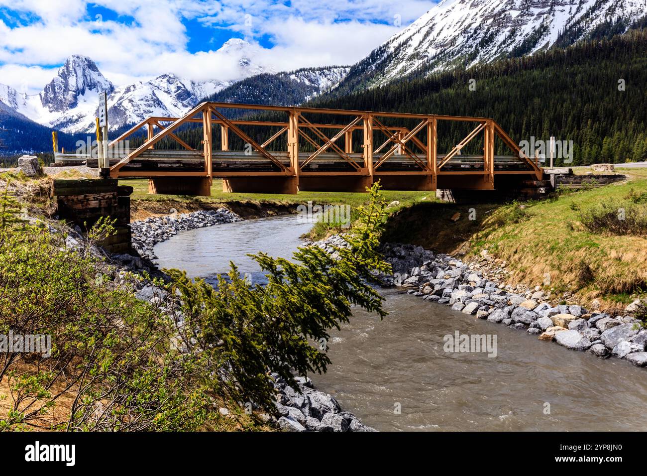 Eine Brücke überspannt einen Fluss mit einem Berg im Hintergrund. Die Brücke ist aus Holz und erstreckt sich über die gesamte Breite des Flusses Stockfoto