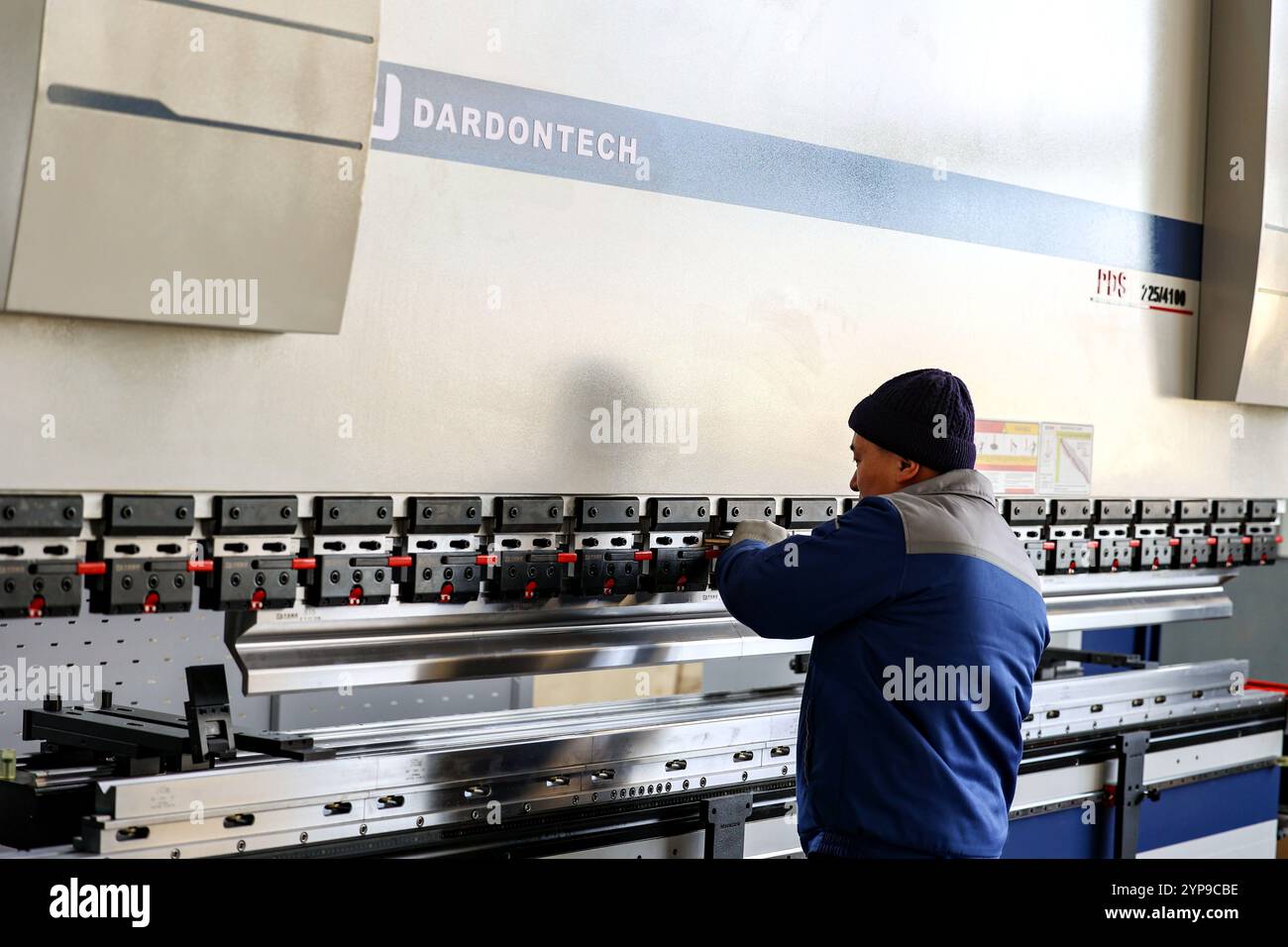 QINGDAO, CHINA – 29. NOVEMBER 2024 – Ein Arbeiter produziert eine Faserlaserschneidemaschine auf einer flexiblen Produktionslinie in einer digitalen Produktionswerkstatt in Stockfoto