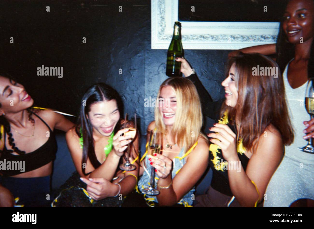 Eine Gruppe von Freunden feiert fröhlich mit Champagner im Vintage-Retro-Stil mit nostalgischer und staubiger Ästhetik. Stockfoto