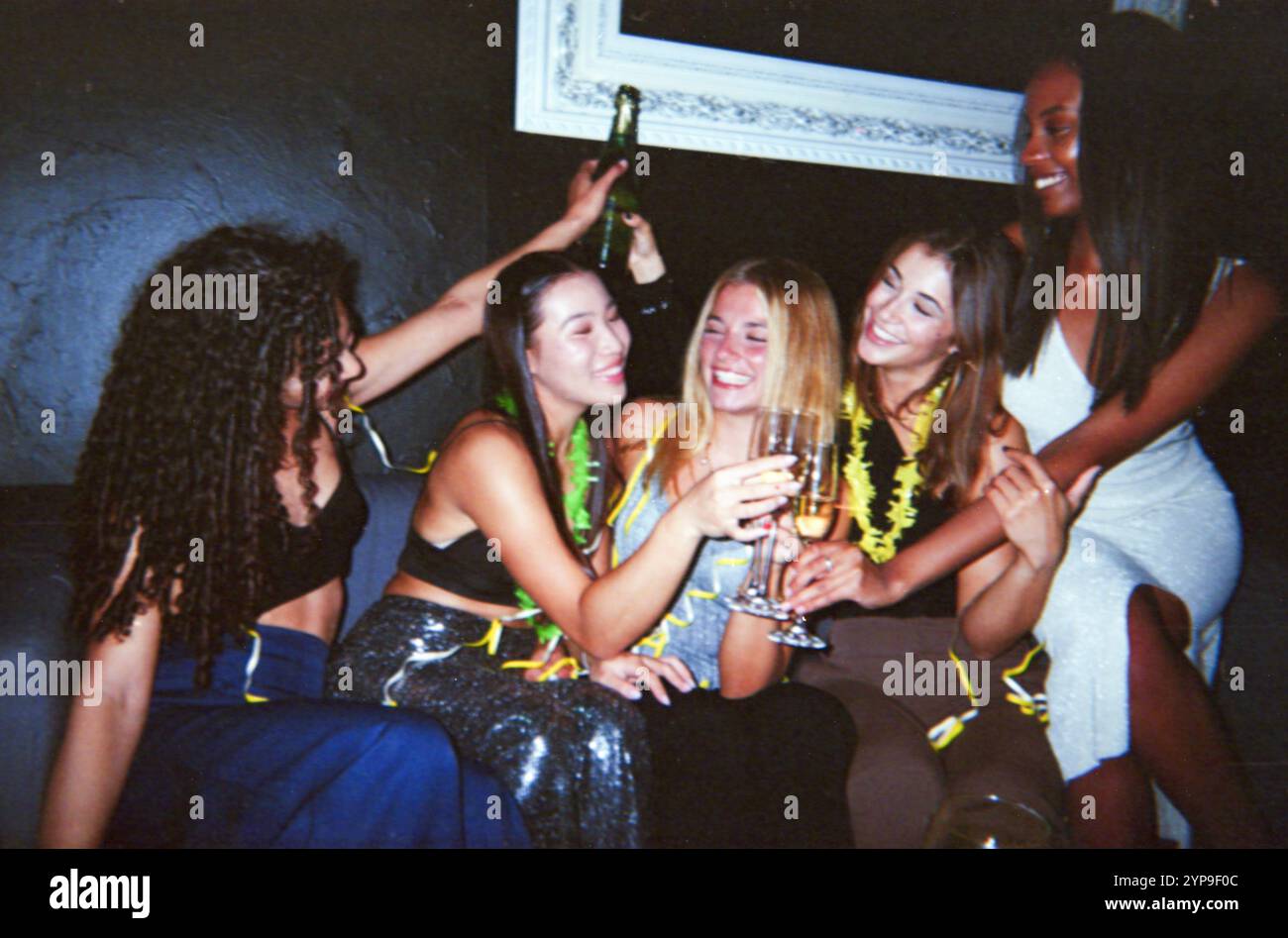 Eine Gruppe von Freunden feiert mit Champagner und hält einen fröhlichen Moment in einer Vintage-Filmkamera mit einem staubigen und zerkratzten Effekt fest. Stockfoto