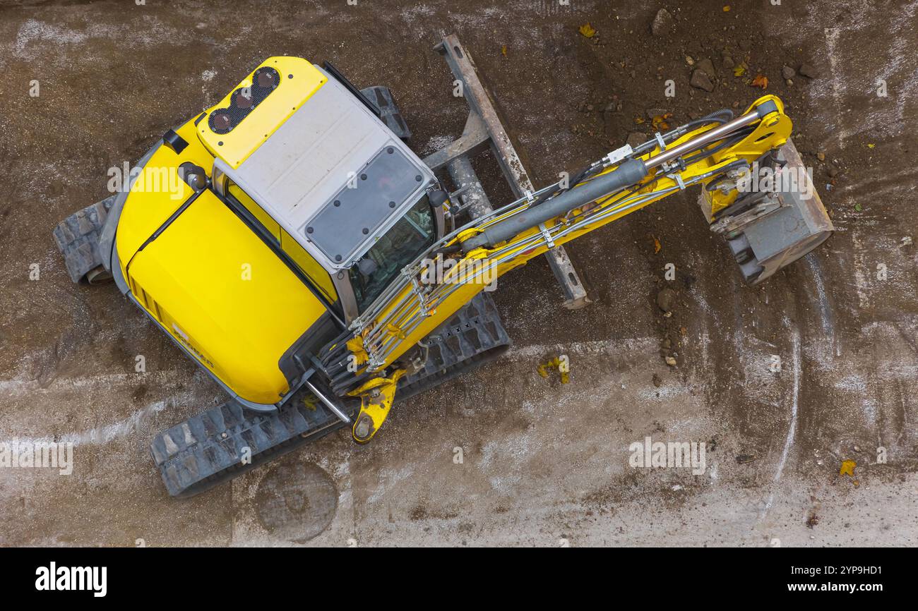 Minibagger graben Boden auf der Baustelle. Ansicht von oben. Kompakte Baumaschinen. Erdarbeiten, Aushub. Minibagger mit buc Stockfoto