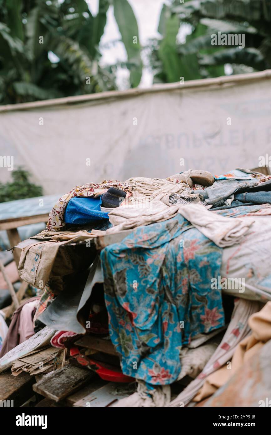 Ein Haufen abgenutzter und unbrauchbarer Kleidung, die in einem Abfalleimer entsorgt wird, symbolisiert Abfall und Umweltprobleme Stockfoto