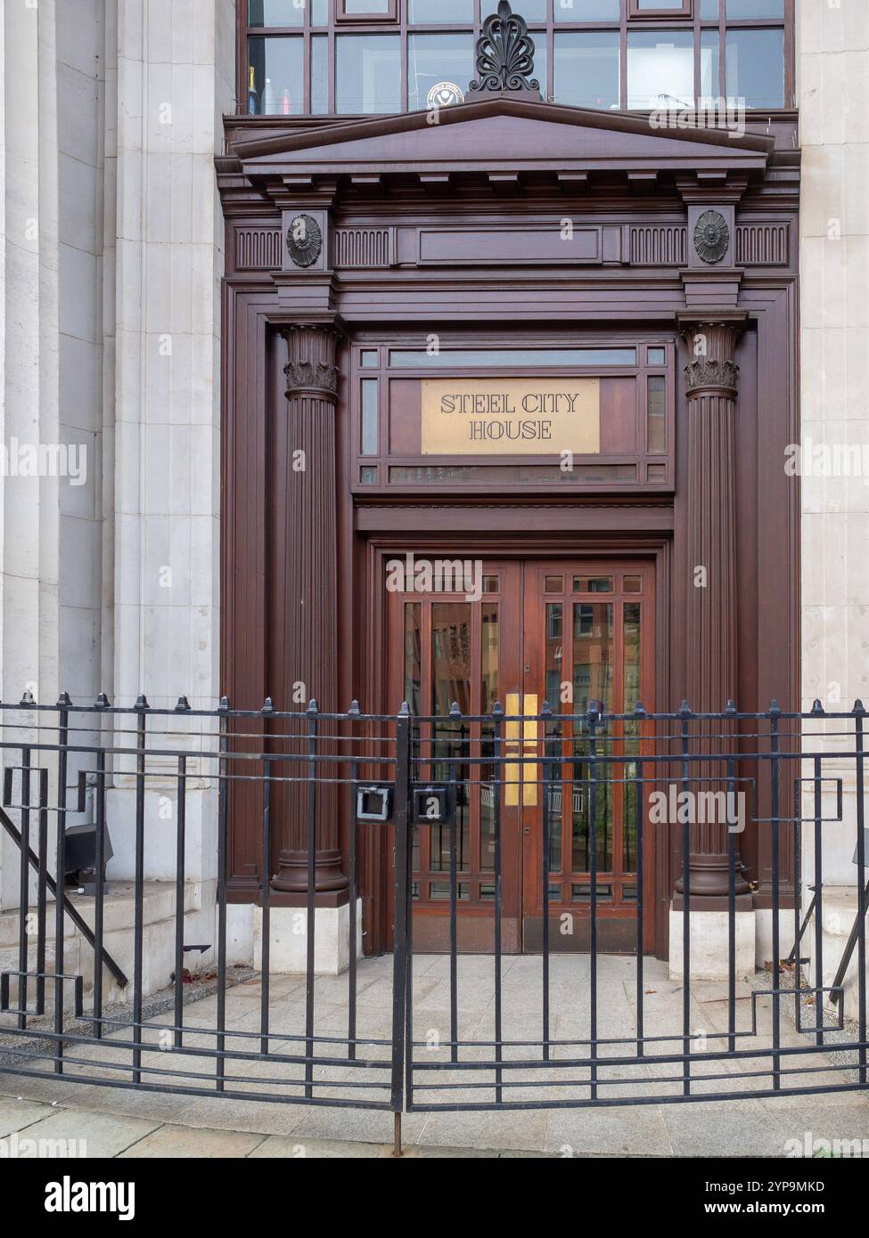 Imposanter und prachtvoller Holzeingang zum Steel City House Gebäude in Sheffield, Großbritannien hinter einem Metalltor. Das 1927 erbaute Gebäude ist heute ein Büro. Stockfoto