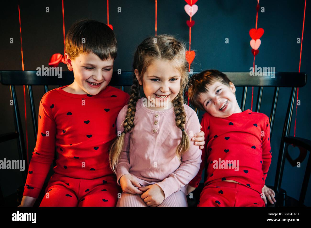 Drei lachende Kinder mit Valentinstag-Herzdekoration Stockfoto