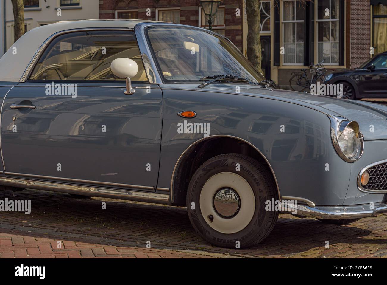 Nahaufnahme eines alten Nissan Figaro blauen Retro-Autos, der auf der Straße geparkt ist Stockfoto