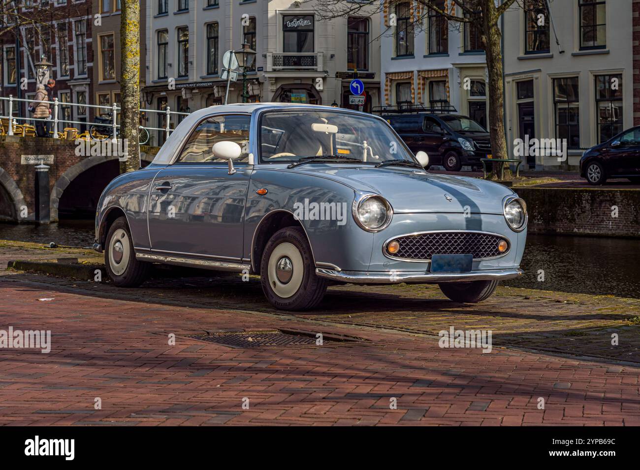 Blaues Retro-Auto von Nissan Figaro parkte an einem sonnigen Tag auf der Straße Stockfoto