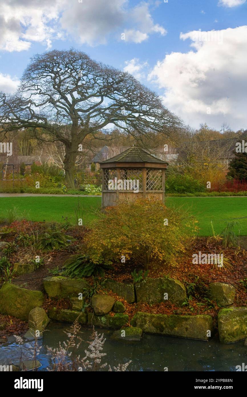 Eine herbstliche Szene mit einem ruhigen Steingarten, hölzernen Pavillon und einem flachen Bach, RHS Garden, Harlow Carr, Harrogate, Yorkshire. Stockfoto