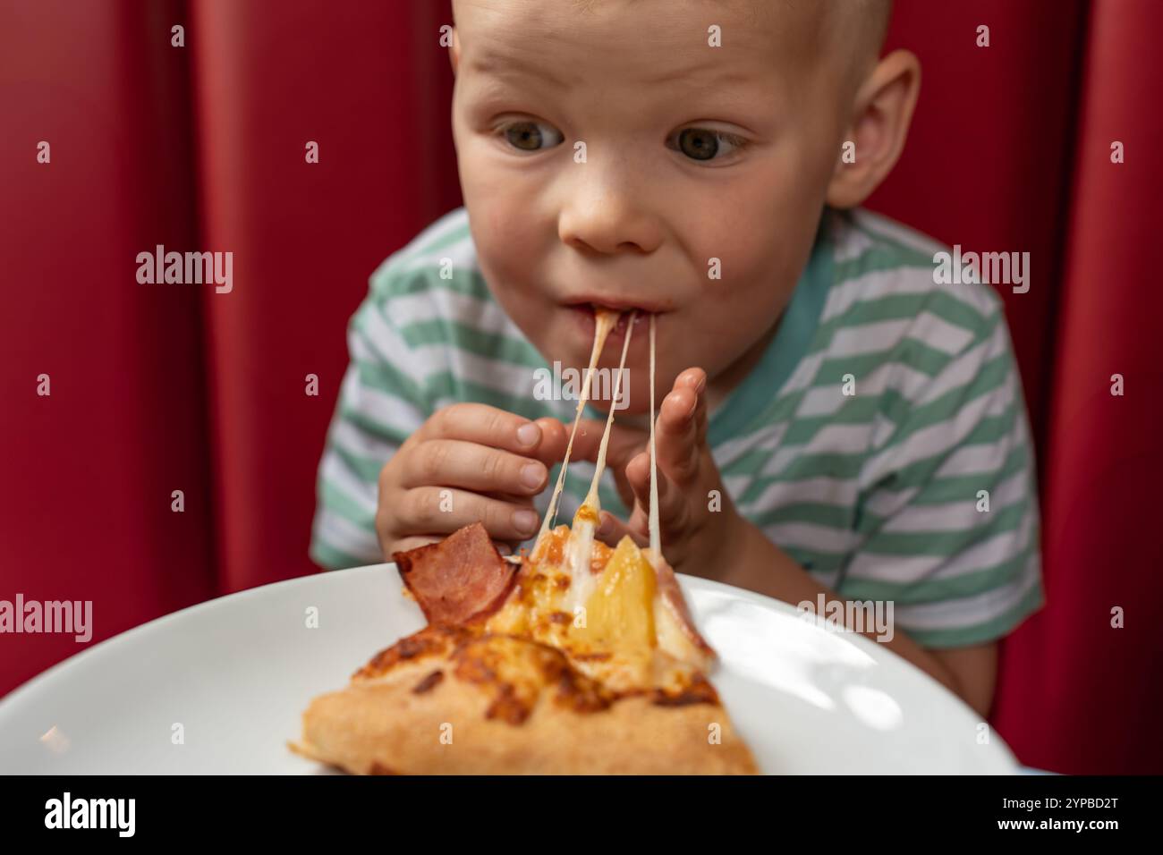Nahaufnahme eines Kindes eVergessen eines Kindes, das eine große Pizza genießt. Mahlzeiten für Kinder auf Reisen. Ungesunde Nahrung. Ich freue mich über eine große Pizza. Kind Stockfoto