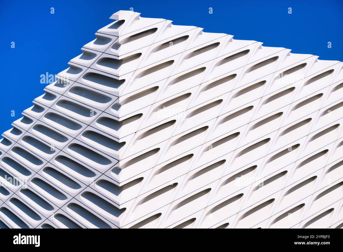 Nahaufnahme eines modernen architektonischen Gebäudes mit weißen Gittern vor einem klaren blauen Himmel, das zeitgenössische Designelemente zeigt. Stockfoto