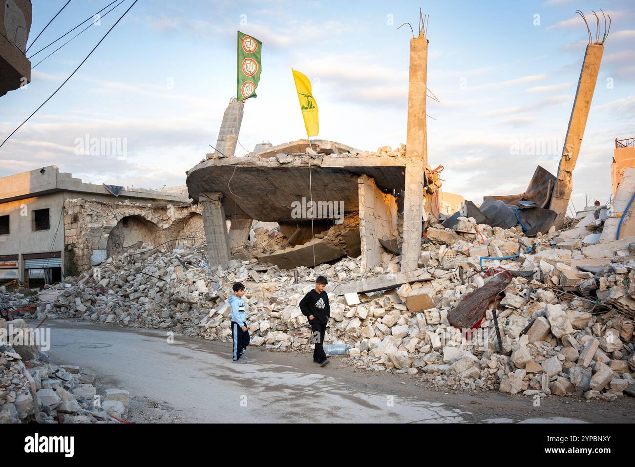 Zwei Kinder gehen am zweiten Tag des Waffenstillstands vor einem Gebäude, das durch Beschuss in der südlibanesischen Stadt Tyr zerstört wurde. Der Krieg zwischen der Hisbollah und Israel führte dazu, dass 1,3 Millionen Menschen aufgrund von Bombenanschlägen aus ihren Häusern flohen und mindestens 4.000 Menschen starben. Nach dem Waffenstillstand am 26. November wurden die Straßen des Libanon nach Dahiye und in die südlichen Städte mit einer großen Anzahl von Wohnwagen gefüllt, die in ihre Heimat zurückkehrten. Stockfoto