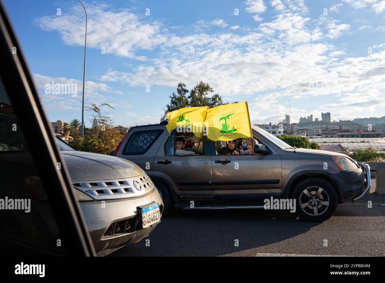 Nabatieh, Libanon. November 2024. Die Menschen halten Hisbollah-Fahnen in einem Auto auf der Straße von Beirut in den Südlibanon am zweiten Tag des Waffenstillstands. Der Krieg zwischen der Hisbollah und Israel führte dazu, dass 1,3 Millionen Menschen aufgrund von Bombenanschlägen aus ihren Häusern flohen und mindestens 4.000 Menschen starben. Nach dem Waffenstillstand am 26. November wurden die Straßen des Libanon nach Dahiye und in die südlichen Städte mit einer großen Anzahl von Wohnwagen gefüllt, die in ihre Heimat zurückkehrten. (Credit Image: © Ximena Borrazas/SOPA images via ZUMA Press Wire) NUR REDAKTIONELLE VERWENDUNG! Nicht für kommerzielle ZWECKE! Stockfoto