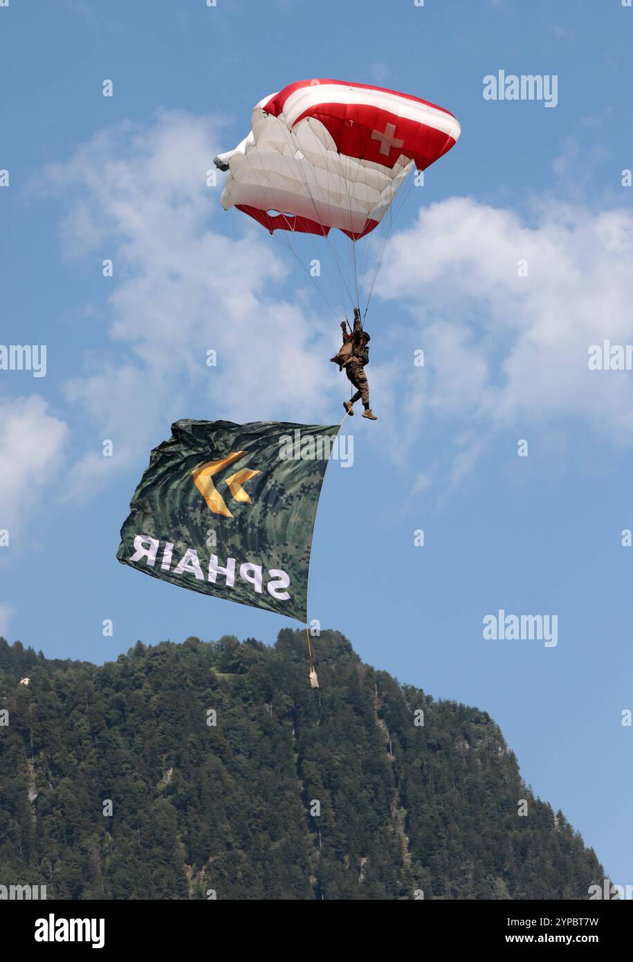 Ein Fallschirmspringer der Schweizer Armee, ein Fallschirm-Displayteams der Schweizer Armee, an einem Freifallschirm mit der Flagge SPHAIR. Hochkant. Die Flugshow ZigAirMeet mit internationaler Beteiligung aus dem militärischen und zivilen Luftfahrtbereich fand am 18. Und 19. August 2023 in Mollis, Kanton Glarus, Schweiz, statt. Mollis Glarus Schweiz *** Fallschirmspringer der Schweizer Parawings, ein Fallschirmspringteam der Schweizer Armee, auf einem Freifallfallfallschirm mit der Flagge SPHAIR aufrecht die ZigAirMeet Luftschau mit internationaler Beteiligung aus dem Militär- und Zivilluftfahrtsektor t Stockfoto