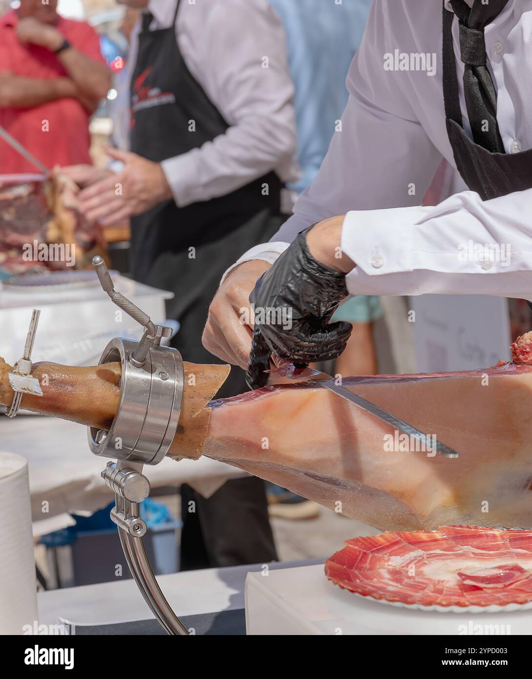 Iberischer Schinken in einen Schinkenhalter gelegt, von Hand und mit einem Messer von einem professionellen Schneider geschnitten. Stockfoto