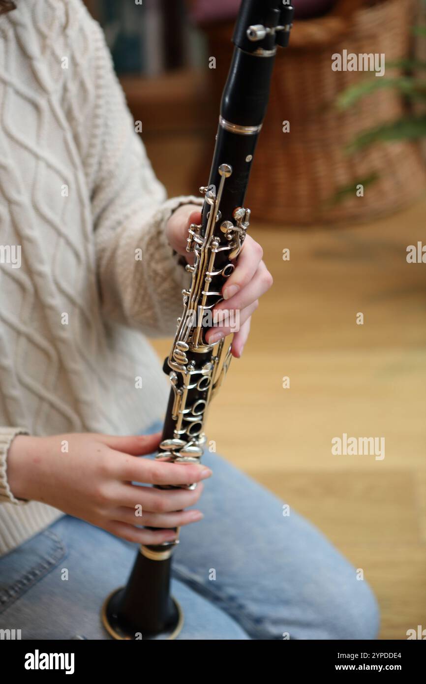 Teenager-Mädchen, das Klarinette zusammenstellt, bevor sie Klarinette im Wohnzimmer spielt Stockfoto