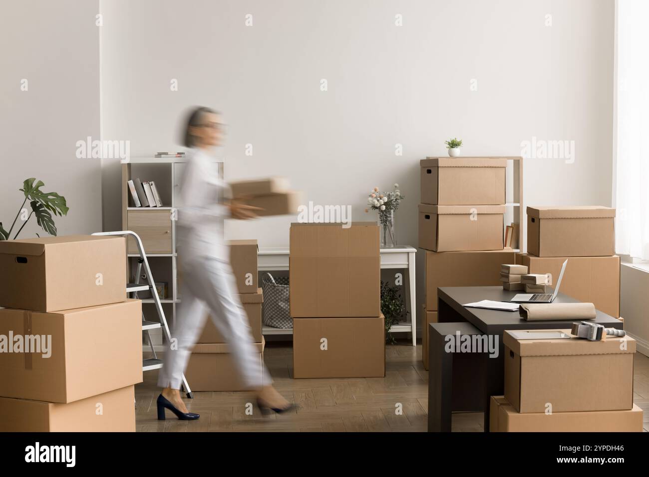 Verschwommenes Bild einer reifen Geschäftsinhaberin mit Kartonschachteln Stockfoto