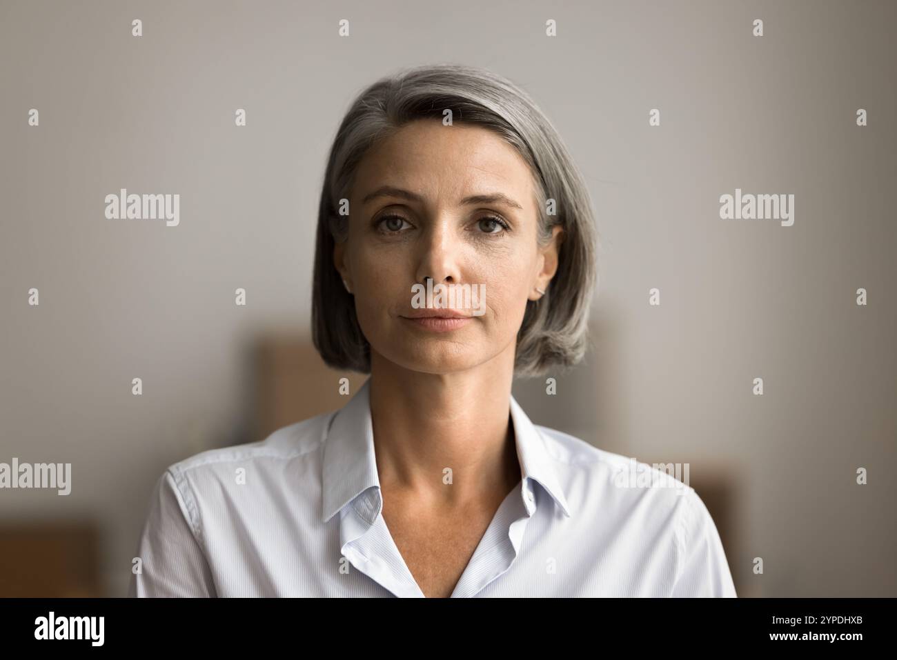 Selbstbewusste, ernste, reife Geschäftsfrau, die drinnen steht Stockfoto