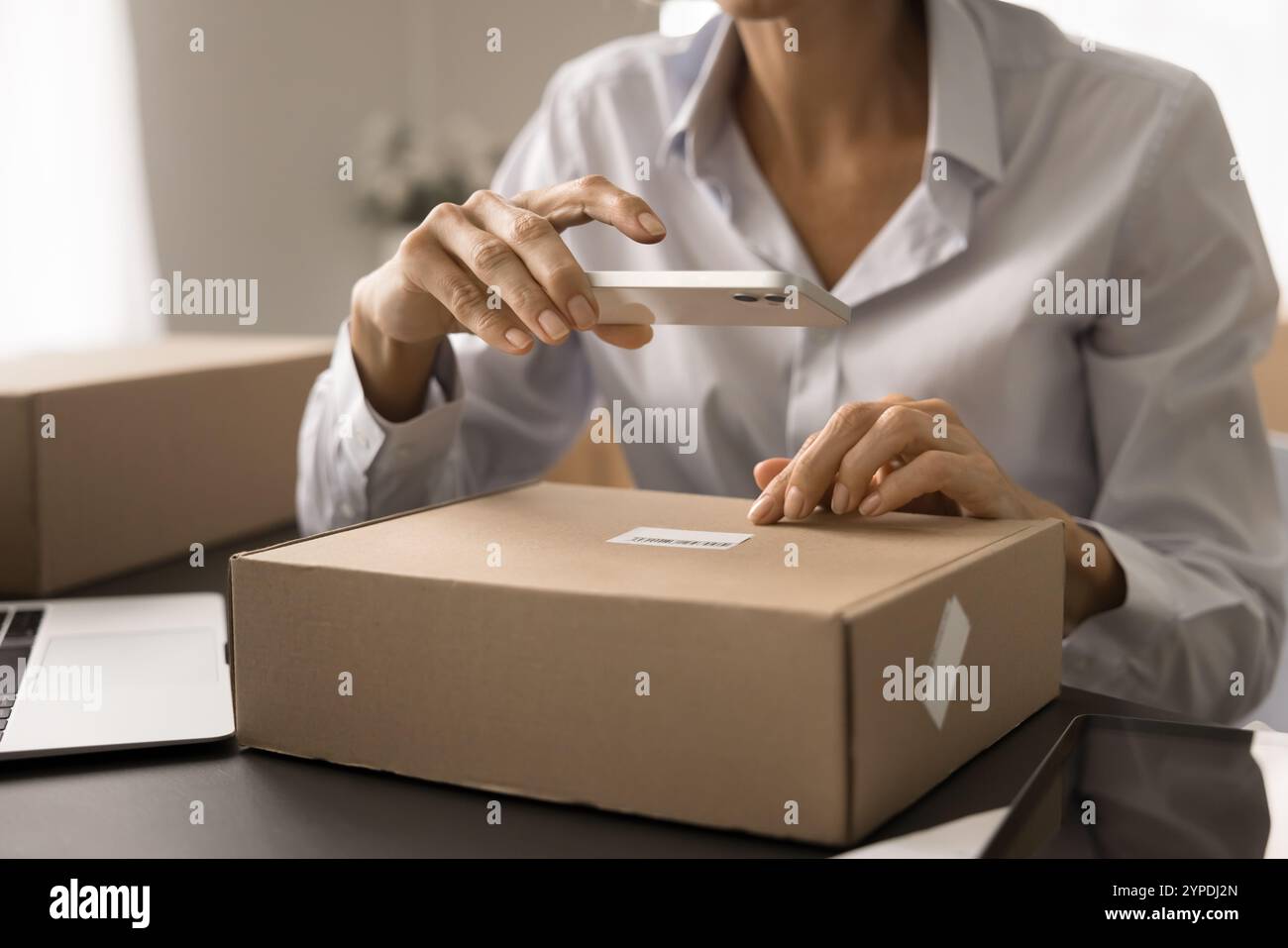 Reife E-Commerce-Speicherarbeiterin, die ein Mobiltelefon benutzt Stockfoto