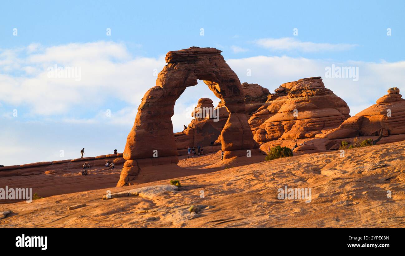 Moab, UT, USA – 11. Juni 2024; Touristen erkunden die rote Felsenlandschaft rund um Delicate Arch im Arches National Park Stockfoto