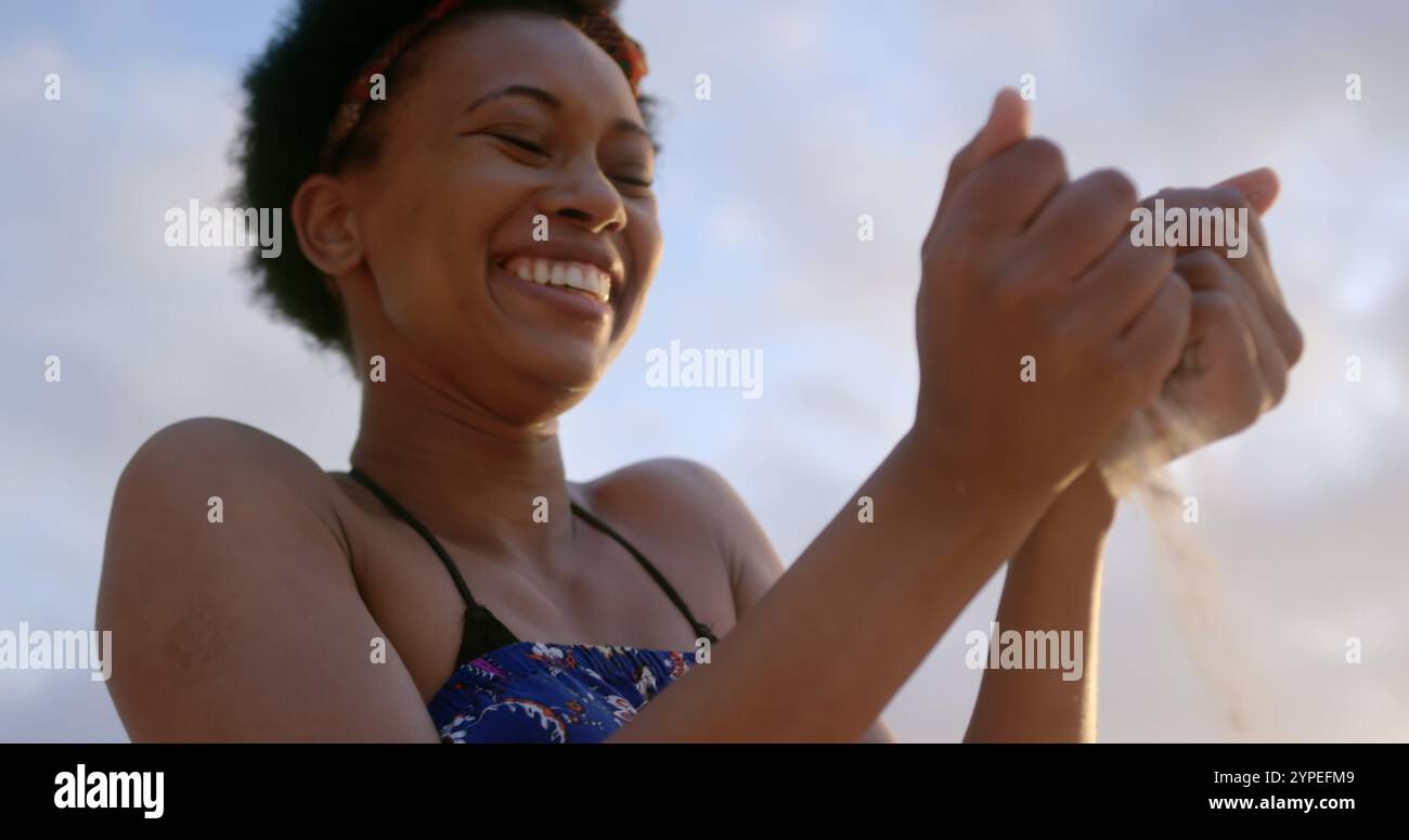 Niedriger Blick auf die afroamerikanische Frau, die am Strand mit Sand spielt Stockfoto