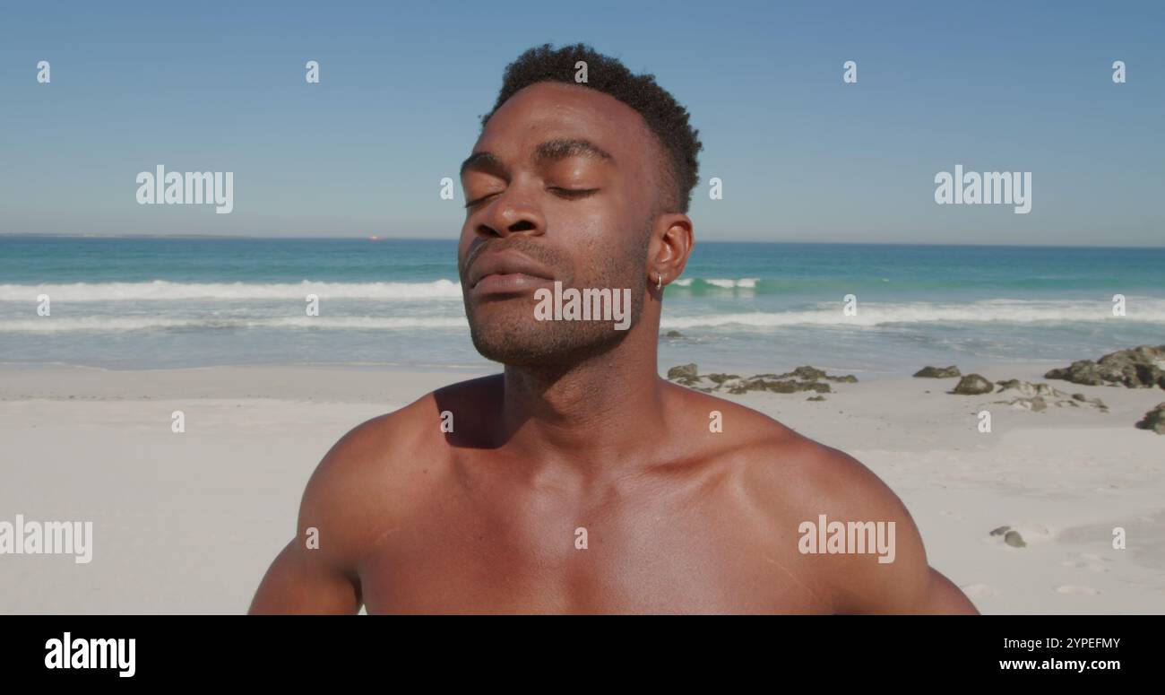 Nahaufnahme eines jungen afroamerikanischen Mannes, der Zeit zur freien Verfügung an einem sonnigen Strand am Meer genießt Stockfoto