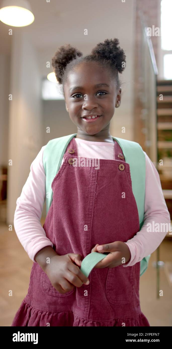 Vertikales Bild des Porträts eines glücklichen afroamerikanischen Mädchens zu Hause, Zeitlupe Stockfoto