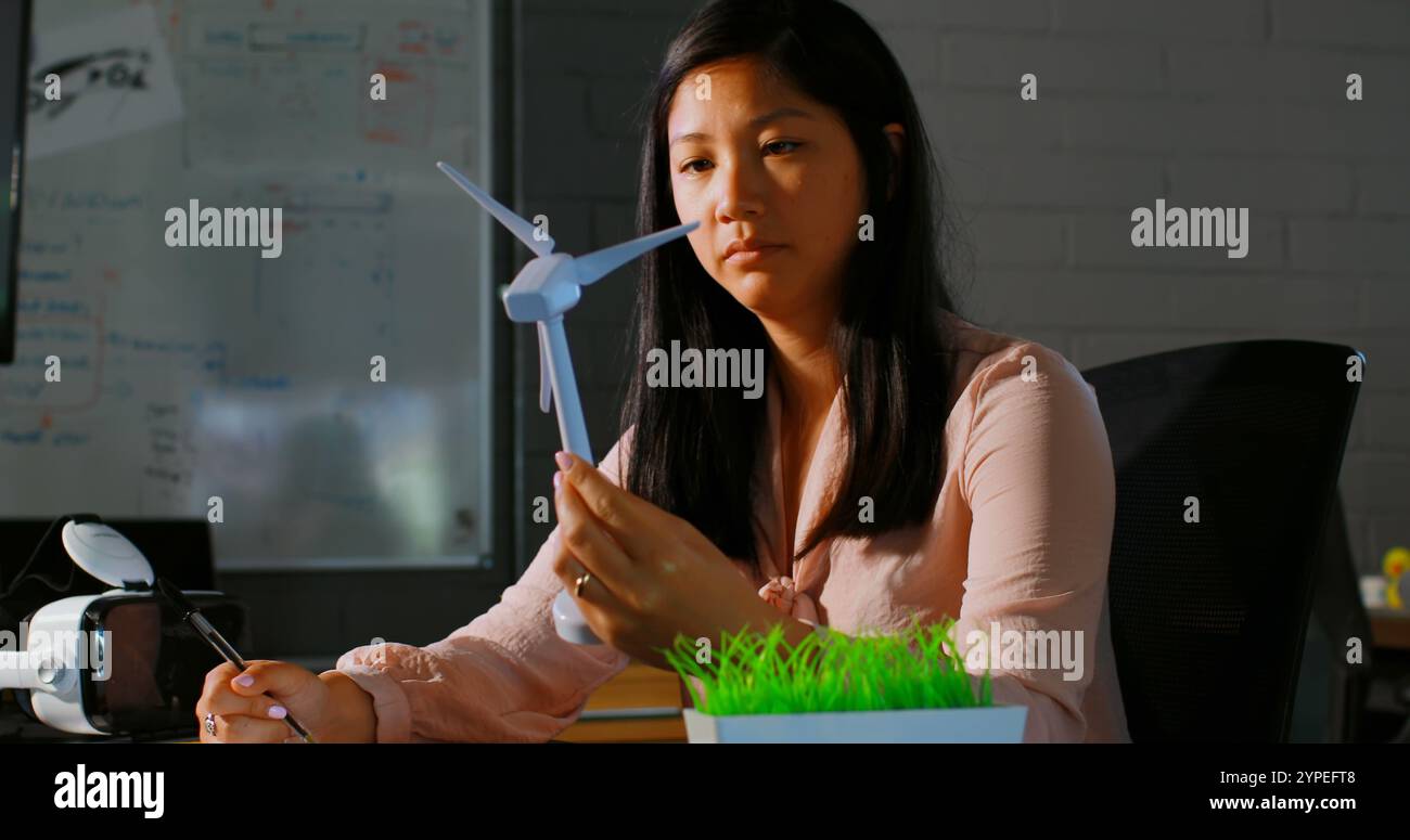 Weibliche Führungskraft untersucht ein Windmühlenmodell im Büro Stockfoto