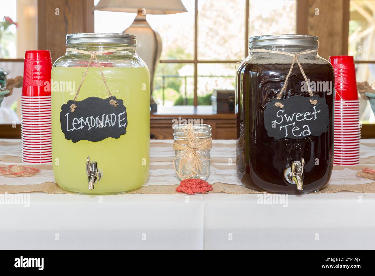 Einmachgläser mit Limonade und süßem Tee mit roten Plastiktassen auf einer rustikalen Landhochzeit Stockfoto