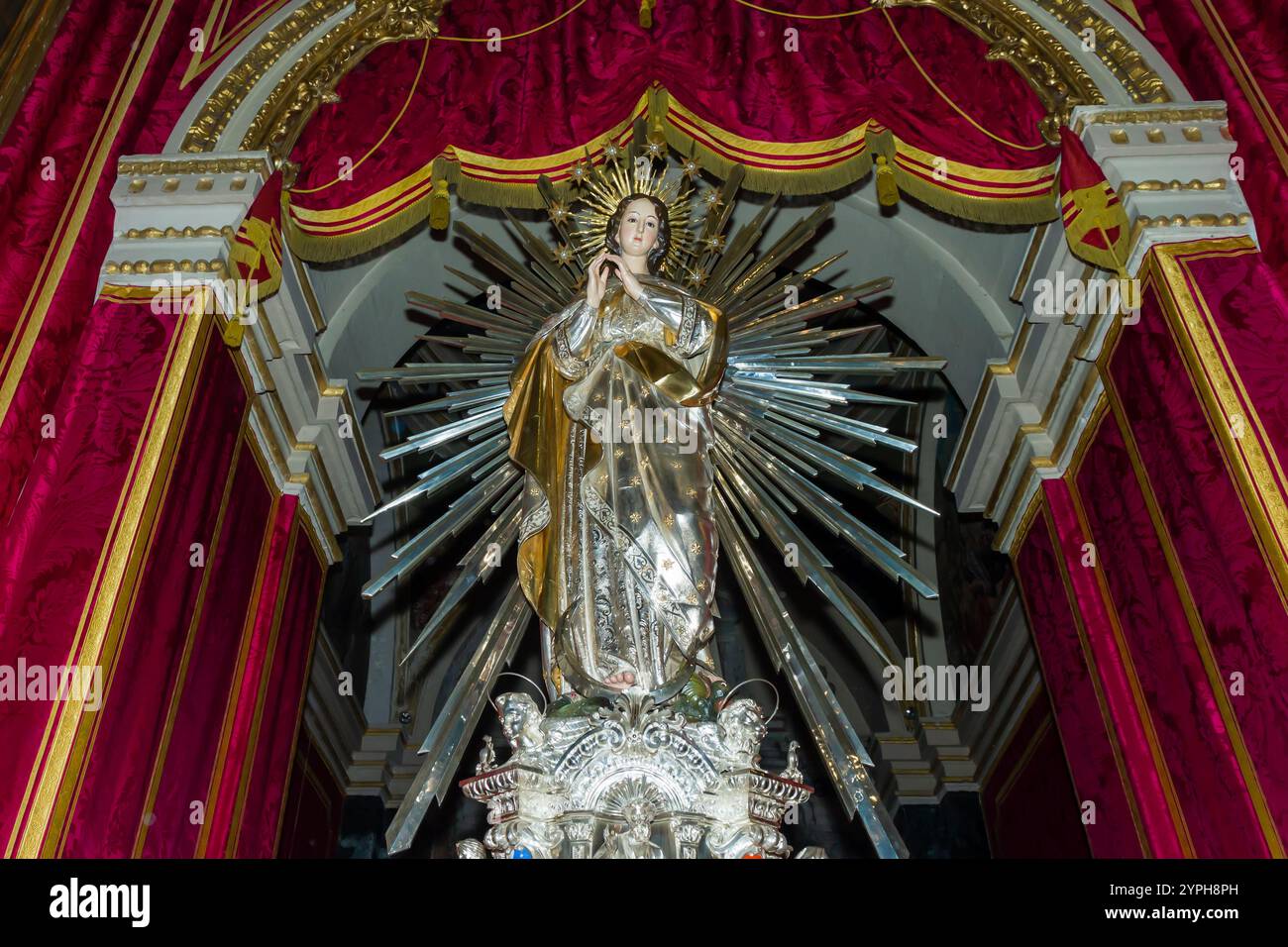 Cospicua, Malta - 28. November 2024. Majestätische Religiöse Statue Umgeben Von Roten Samtvorhängen In Der Kunstvollen Kirche Stockfoto