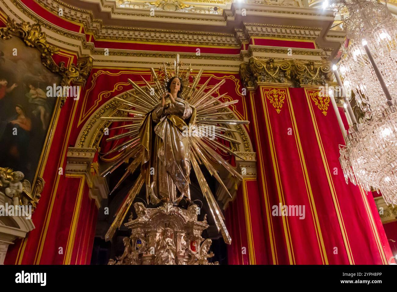 Cospicua, Malta - 28. November 2024. Majestätische religiöse Statue im prunkvollen Inneren der Kathedrale mit roten Vorhängen Stockfoto
