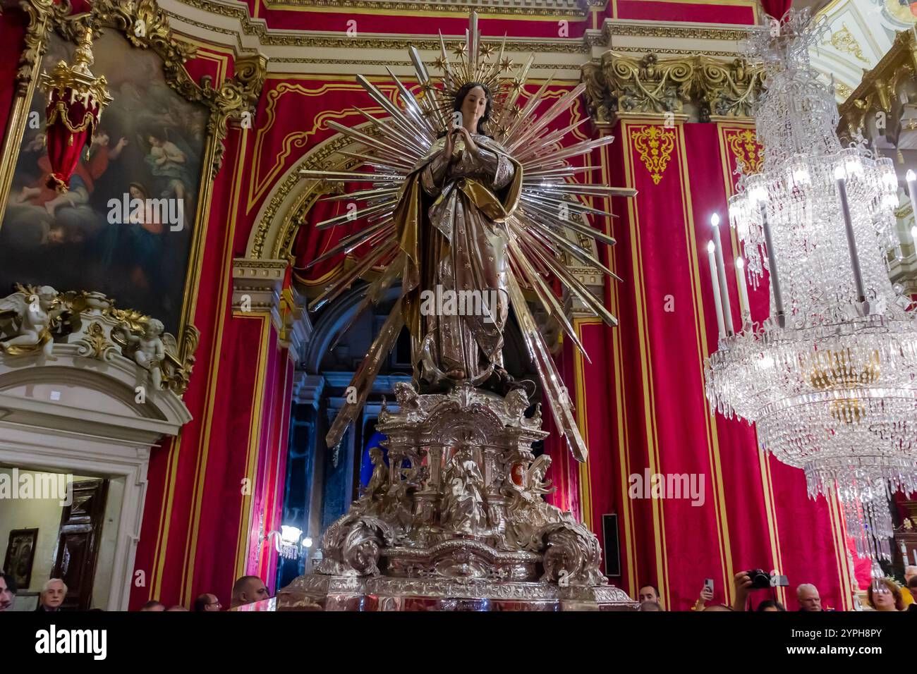 Cospicua, Malta - 28. November 2024. Verzierte religiöse Statue in einem üppigen Inneren der Kathedrale mit roten Vorhängen Stockfoto