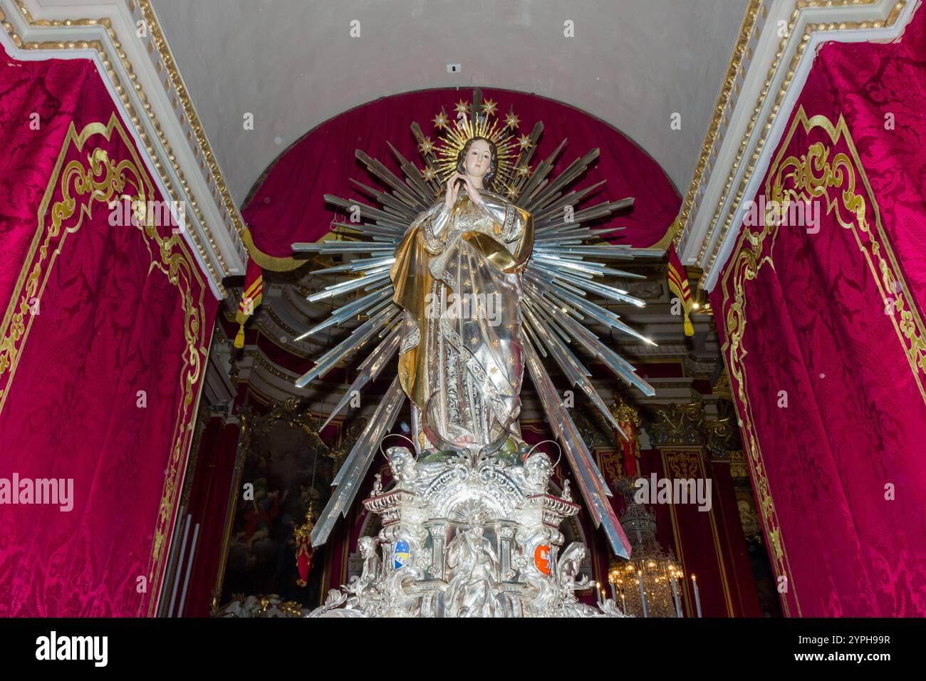 Cospicua, Malta - 28. November 2024. Verzierte religiöse Statue mit komplizierten Golddetails in üppiger kirchlicher Umgebung Stockfoto