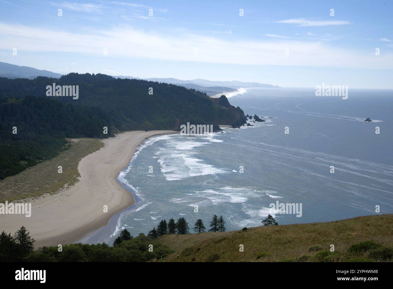 Blick auf den Pacific Coast Beach, insbesondere zwischen Cascade Head und God's Daume, unter einem friedlichen, sonnigen Tag neben einem ruhigen, glitzernden Meer. Stockfoto