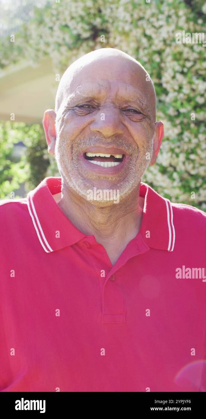Vertikales Bildporträt eines glücklichen älteren, birassischen Mannes, der im Garten lacht Stockfoto