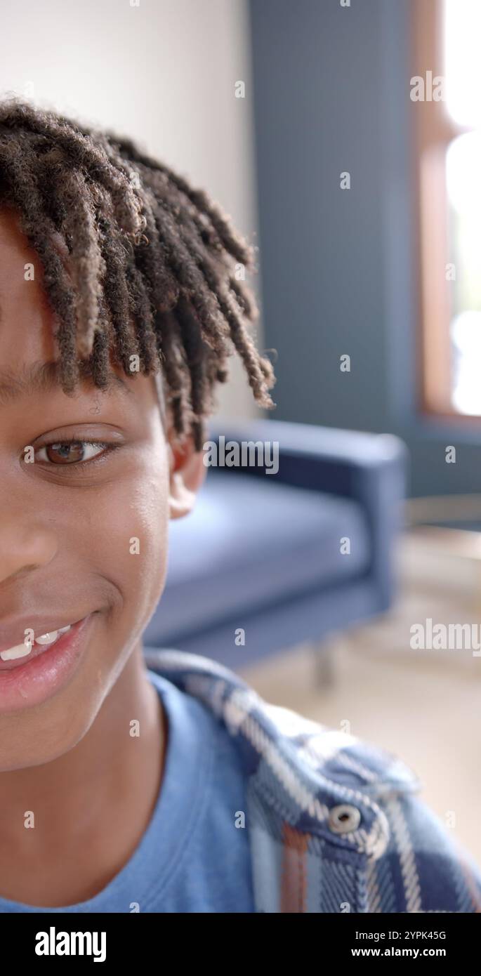 Vertikales Bild des Porträts eines glücklichen afroamerikanischen Jungen, der zu Hause lächelt Stockfoto