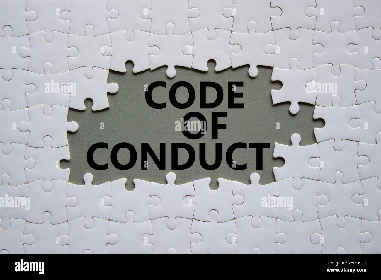 Symbol für Verhaltenskodex. Weißes Puzzle mit Worten Verhaltenskodex. Schöner grauer Hintergrund. Business and Code of Conduct Konzept. Kopierbereich. Stockfoto